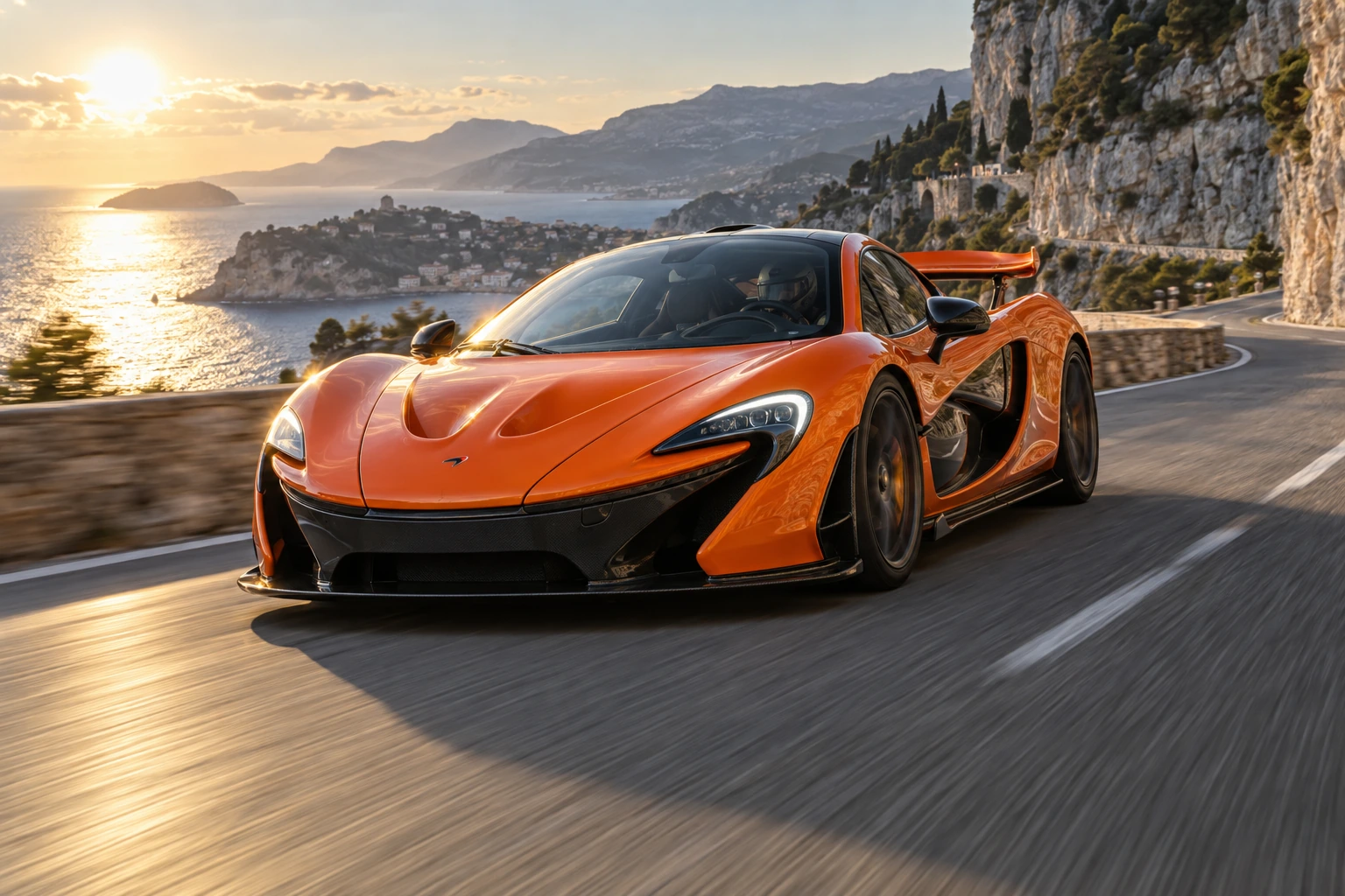 Low frontal three-quarter view of an orange McLaren P1 speeding along a coastal road with blurred asphalt